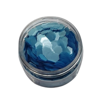 Blaue Glitzerflocken (C0506) in einem klaren Glas auf schwarzem Hintergrund, hergestellt von FLEURY.
